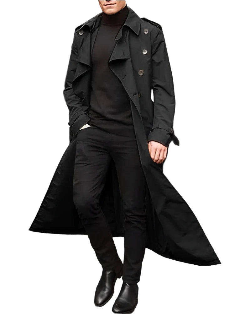 Person wearing a long black coat on a city street.