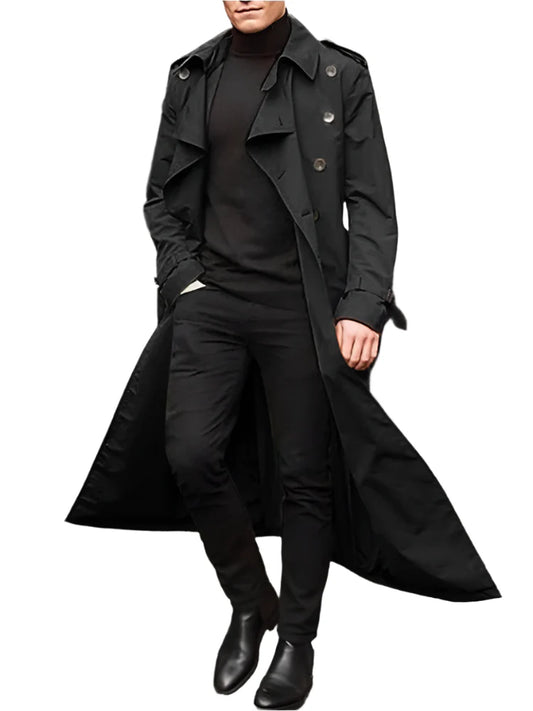 Person wearing a long black coat on a city street.